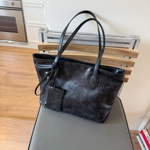 Detailed view of large black tote bag with vintage texture and small zipper pouch