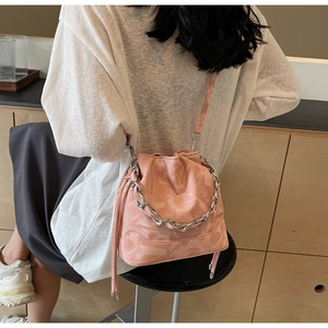 Détail du sac seau rose clair avec motifs gaufrés et bandoulière en chaîne argentée