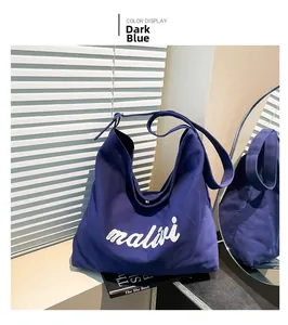 Detailed view of dark blue canvas tote bag with white malivi lettering on wood surface