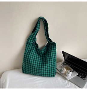 Detail of green and black gingham canvas tote bag with shoulder strap and brand label