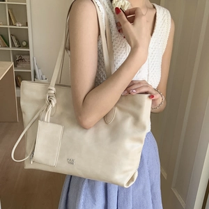 Detail view of beige large tote bag with knot strap design and small hanging pouch