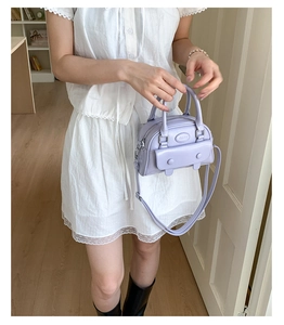 Lifestyle shot showing a light purple mini Boston bag with dual buckles and adjustable strap