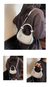 Detail view of a silver crescent moon bag with circular handle and metallic finish