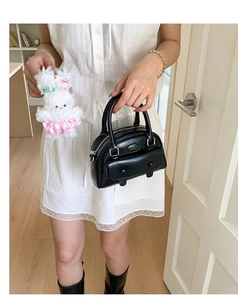 Detail of black leather Boston bag with vintage doctor silhouette and plush rabbit charm