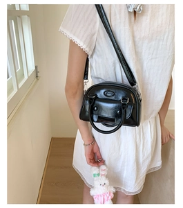 Detail of black glossy mini tote bag with push-button pocket and plush bunny pendant