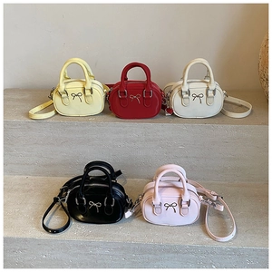 Five colorful mini bowling bags with bow hardware displayed on grey stone stairs
