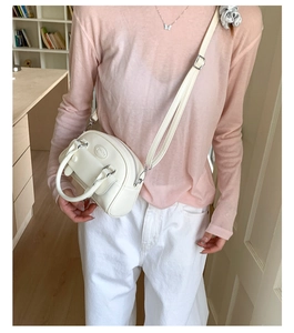 Detail of minimalist cream leather handbag with adjustable long strap and top handle