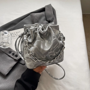 Détail du sac seau gris argenté avec imprimé graffiti et bandoulière en chaîne argent