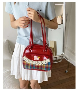 Détail du sac à main en cuir verni rouge avec dentelle et broderie cerise