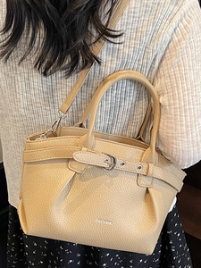 Chic beige ruched bucket bag in lychee leather, worn by model for summer daily commute