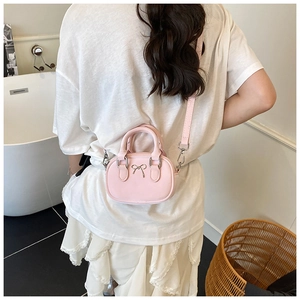 Pink mini bowling bag shown on shoulder in a lifestyle setting for size perspective