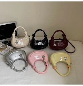 Group shot of colorful patent leather crescent handbags with branded metal charms and straps
