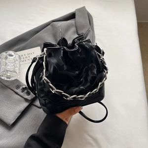 Détail du sac seau noir à cordon avec chaîne argentée et finition jacquard mate