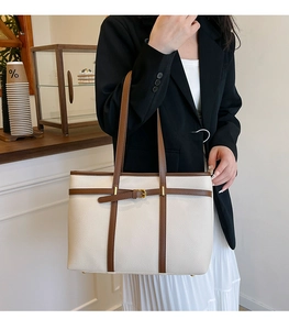 Chic off-white textured leather tote bag with dark brown trim detail in cafe setting
