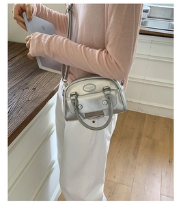 Detail view of a silver metallic mini boston bag with handle and adjustable strap