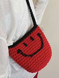 Handmade red knit bucket bag with a black smiley face design and crochet strap