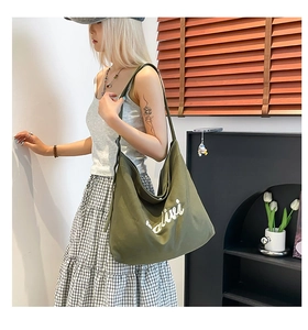 Detailed view of olive green canvas tote bag with white alive embroidery and wide strap