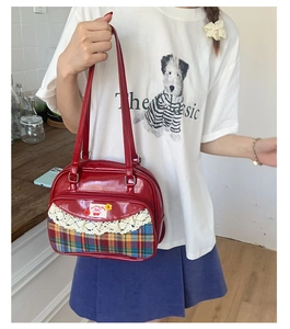 Détail du sac en cuir verni rouge avec bordure en tissu écossais et dentelle cerise