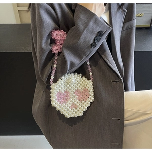 Detail of handmade beaded handbag with white round beads and pink heart pattern design