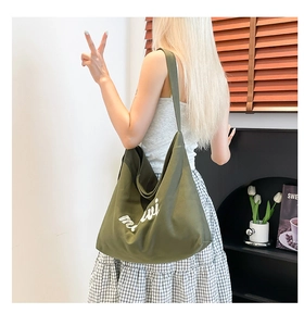 Detail of army green canvas tote bag featuring white cursive embroidery and large capacity