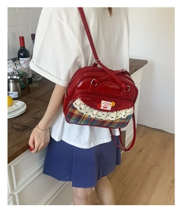Gros plan du sac à main rouge brillant avec dentelle blanche et broderie de cerises