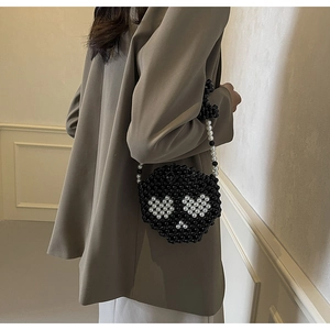 Detailed back view of a mini beaded crossbody bag with a heart face design on a model