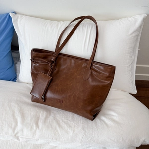 Detail shot of brown leather tote bag with PAN TOR logo and small matching coin purse