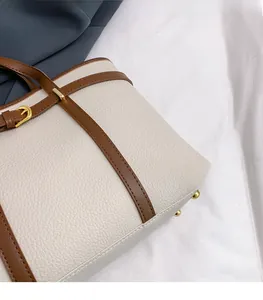 Detail of off-white lychee grain leather tote bag with brown straps and gold hardware