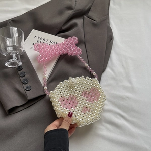 Detail of handmade pearl mini bag featuring pink beaded heart and large bow handle