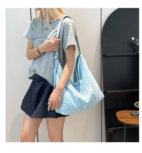 Detail of light blue canvas tote bag with Livi embroidery and adjustable strap