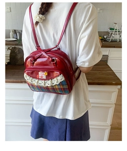 Détail du sac bowling en cuir verni rouge avec dentelle et écusson cerise