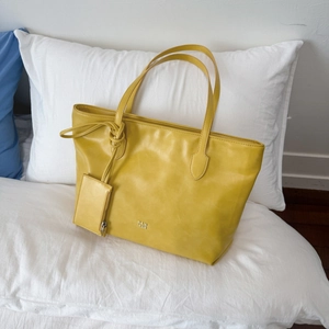 Detail of yellow leather tote bag showing fine texture and PANTOR brand logo