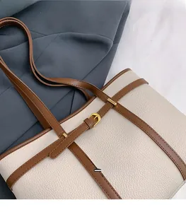 Close-up of off-white lychee grain leather tote bag with brown straps and gold buckle