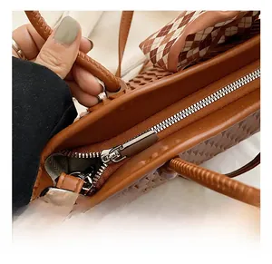 Close-up of brown woven leather tote bag featuring durable silver metal zipper and hardware