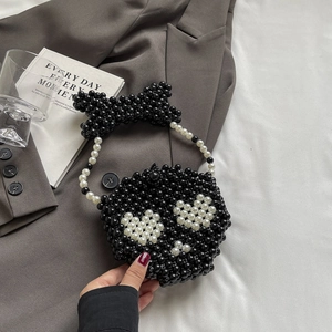 Macro shot of handcrafted black beaded mini bag with pearl bow and crossbody chain detail