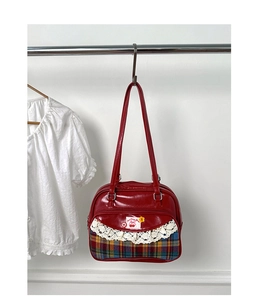 Détail d'un sac à main rouge avec bordure en dentelle et motif à carreaux écossais