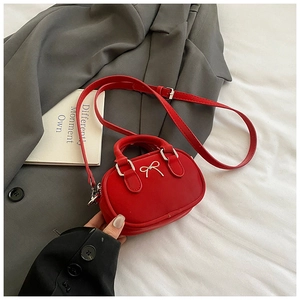 Close-up of a mini red leather bowling bag with silver metal bow and adjustable strap