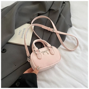 Detail of light pink mini bowling bag with silver metal bow and detachable shoulder strap