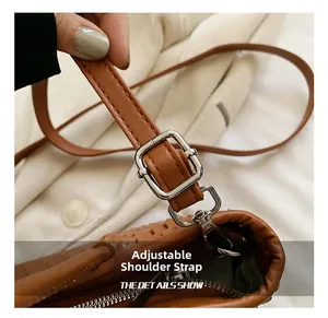 Detail showing adjustable brown leather shoulder strap with silver metal buckles and hooks
