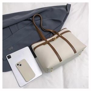 Flat lay of cream leather tote bag with brown straps alongside a tablet and suit