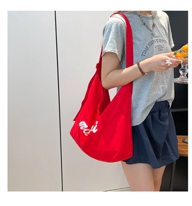 Detailed side view of large red canvas tote bag with white cursive letter embroidery