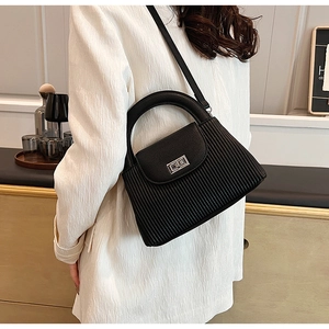 Detail of black pleated crossbody bag with silver twist lock and slim shoulder strap