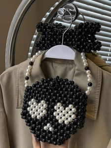 Handmade beaded handbag with black and white heart patterns and a bow charm