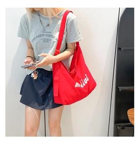 Close-up of red canvas tote bag showing high-capacity design and white cursive lettering