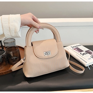 Detail showing apricot striped crossbody bag with elegant silver twist lock and round handle