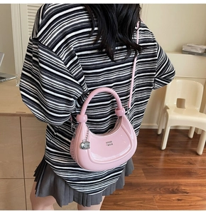 Close-up of pink crescent moon bag with glossy patent finish and silver logo pendant
