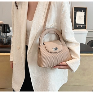 Detail of beige pleated crossbody bag with silver twist lock and round handle