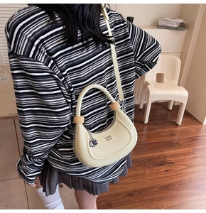 Detail of off-white crescent bag with wooden ball handle and glossy leather finish