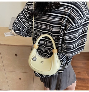 Detail of a creamy yellow half-moon crescent bag with glossy finish and G-pendant