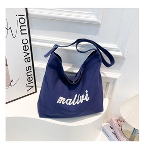 Detail of navy canvas tote bag with white malivi embroidery and adjustable strap